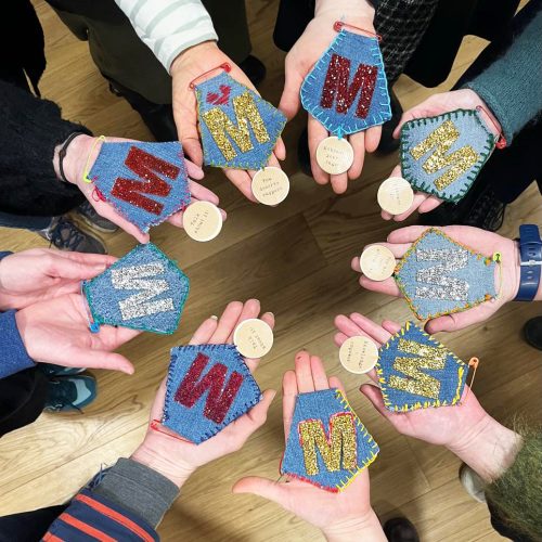 Showing ten hands holding homemae menopause medals from our perimenopause workshop